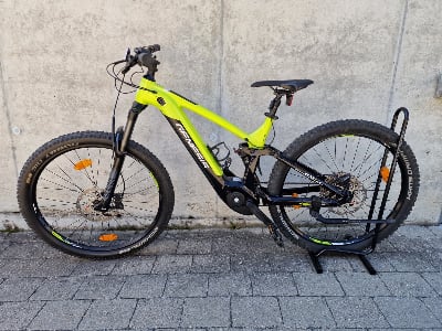 Grünes E-Mountainbike auf einem Ständer vor einer Wand.