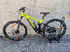 Grünes E-Mountainbike auf einem Ständer vor einer Wand.