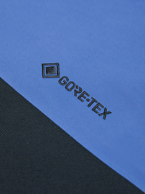 Detail eines Stoffes mit GORE-TEX-Logo auf blauem und schwarzem Hintergrund. Detail eines Stoffes mit GORE-TEX-Logo auf blauem und schwarzem Hintergrund.