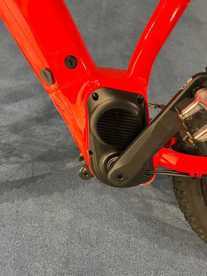 Detail des Rahmens eines roten E-Bikes mit der Abdeckung der Mittelmotoreinheit. Detail des Rahmens eines roten E-Bikes mit der Abdeckung der Mittelmotoreinheit.