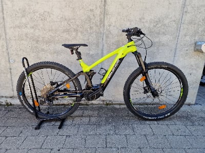 Grünes E-Mountainbike auf einem Ständer vor einer Wand.