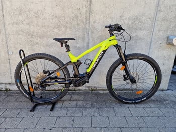 Grünes E-Mountainbike auf einem Ständer vor einer Wand.