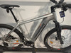 Ein silbernes E-Bike von Genesis mit orangefarbenen Akzenten steht auf einem Ständer.