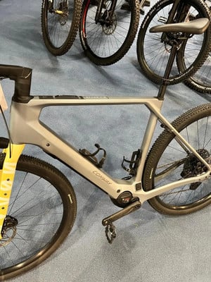 Graues Conway E-Gravelbike mit gelber Vordergabel auf blauem Teppich. Graues Conway E-Gravelbike mit gelber Vordergabel auf blauem Teppich.