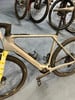 Graues Conway E-Gravelbike mit gelber Vordergabel auf blauem Teppich.