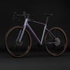 Lila Gravelbike mit braunen Reifen vor schwarzem Hintergrund.
