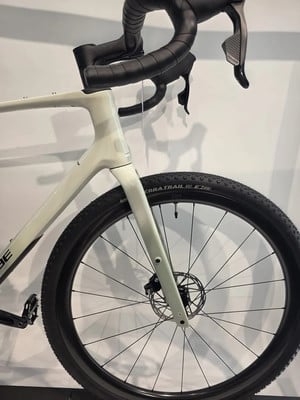 Nahaufnahme des Vorderteils eines weißen Gravelbikes mit Lenker und Rad. Nahaufnahme des Vorderteils eines weißen Gravelbikes mit Lenker und Rad.