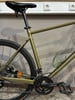 Ein goldenes Fahrrad mit schwarzen Pedalen und Sattel, an der Wand mit Steckdosen.