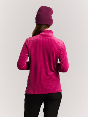Eine Frau von hinten in einem rosa Pullover mit Zopfmuster und lila Mütze. Eine Frau von hinten in einem rosa Pullover mit Zopfmuster und lila Mütze.