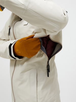 Detail einer Jacke mit Handschuh in der Tasche und offenem Reißverschluss. Detail einer Jacke mit Handschuh in der Tasche und offenem Reißverschluss.