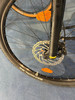Detail eines Mountainbike-Vorderrads mit Scheibenbremse und orangefarbenem Reflektor.