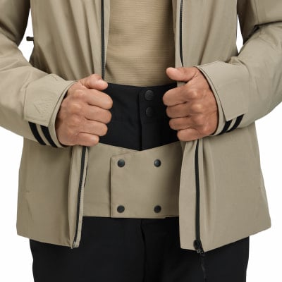 Ein Mann in einer beige Jacke schließt den Reißverschluss und trägt schwarze Hosen. Ein Mann in einer beige Jacke schließt den Reißverschluss und trägt schwarze Hosen.