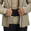 Ein Mann in einer beige Jacke schließt den Reißverschluss und trägt schwarze Hosen.