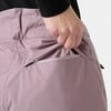 Detail einer Naht und eines Reißverschlusses an einer rosafarbenen Hose, in die eine Hand greift.