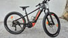 Ein schwarzes KTM E-Bike mit orangefarbenen Details steht vor einer Steinmauer.