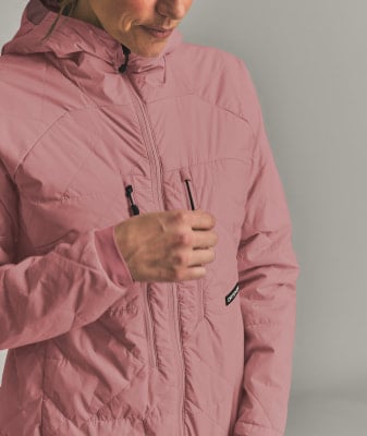 Eine Frau in einer rosafarbenen Kapuzenjacke mit Reißverschluss, ihre Hand in der Tasche. Eine Frau in einer rosafarbenen Kapuzenjacke mit Reißverschluss, ihre Hand in der Tasche.