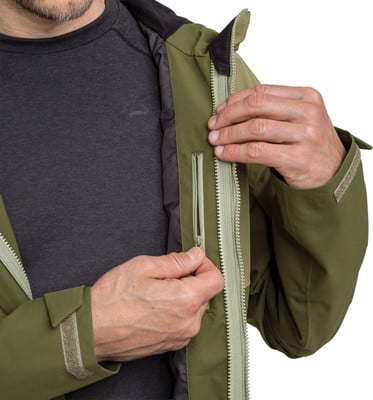 Ein Mann schließt den Reißverschluss einer grünen Jacke über einem dunklen Hemd. Ein Mann schließt den Reißverschluss einer grünen Jacke über einem dunklen Hemd.