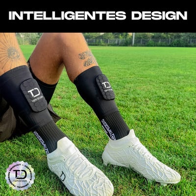 Mann in Schienbeinschonern und weißen Fußballschuhen auf Rasen.