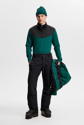 Ein Mann in Skibekleidung hält eine Jacke in der Hand.