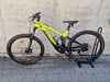Grünes E-Bike der Marke Genesis auf einem Ständer vor einer Wand.