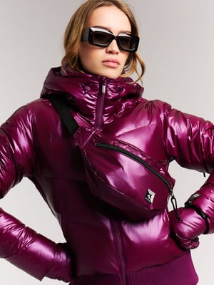 Frau in glänzender weinroter Jacke mit Bauchtasche und Sonnenbrille. Frau in glänzender weinroter Jacke mit Bauchtasche und Sonnenbrille.