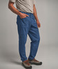 Ein Mann in blauen Hosen mit der Hand in der Tasche und Wanderschuhen.