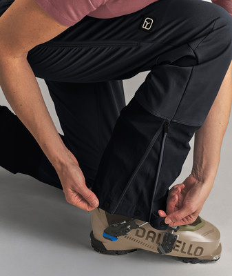 Eine Person schließt eine schwarze Skijacke an einem Dalbello-Schuh. Eine Person schließt eine schwarze Skijacke an einem Dalbello-Schuh.