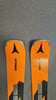Zwei orange Atomic-Ski mit schwarzem Logo auf grauer Oberfläche.