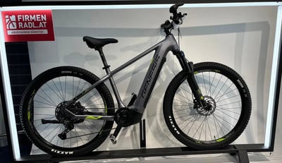 Graues Genesis E-Bike auf einem Ständer mit Beschriftung oben links. Graues Genesis E-Bike auf einem Ständer mit Beschriftung oben links.