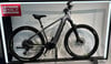 Graues Genesis E-Bike auf einem Ständer mit Beschriftung oben links.