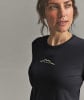 Eine Frau in einem schwarzen T-Shirt mit Berglogo und ORTOVOX-Schriftzug.