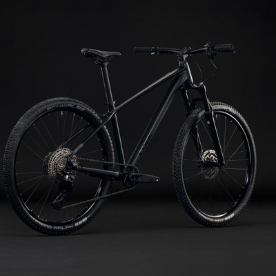 Ein schwarzes Mountainbike mit Federgabel und Scheibenbremsen auf schwarzem Hintergrund.