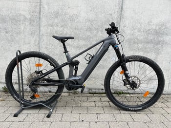 Graues E-Bike der Marke Conway auf einem Ständer vor einer Wand.