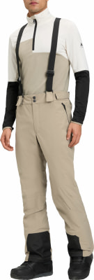 Mann in beiger Skihose mit schwarzen Hosenträgern und Jacke. Mann in beiger Skihose mit schwarzen Hosenträgern und Jacke.