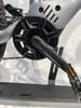 Nahaufnahme von Kurbeln, Pedal und Kette eines E-Bikes auf weißem Hintergrund.