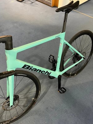 Hellgrünes Bianchi Rennrad mit schwarzen Details auf blauem Teppich. Hellgrünes Bianchi Rennrad mit schwarzen Details auf blauem Teppich.