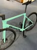 Hellgrünes Bianchi Rennrad mit schwarzen Details auf blauem Teppich.