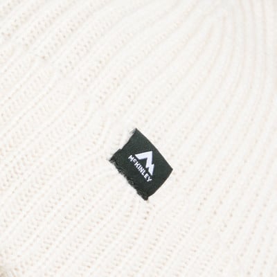 Eine weiße Strickmütze mit schwarzem McKinley-Patch und Berg. Eine weiße Strickmütze mit schwarzem McKinley-Patch und Berg.