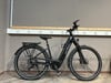 Ein schwarzes KTM E-Bike steht vor einer Wand mit mehreren Steckdosen.
