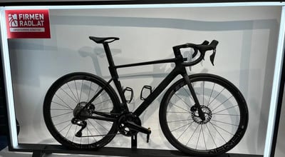 Ein schwarzes Rennrad mit Scheibenbremsen und Firmenlogo auf einem Ständer. Ein schwarzes Rennrad mit Scheibenbremsen und Firmenlogo auf einem Ständer.