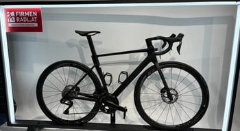 Ein schwarzes Rennrad mit Scheibenbremsen und Firmenlogo auf einem Ständer.