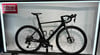 Ein schwarzes Rennrad mit Scheibenbremsen und Firmenlogo auf einem Ständer.