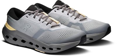 Graue Laufschuhe mit schwarzem Kragen und gelben Details an der Sohle.