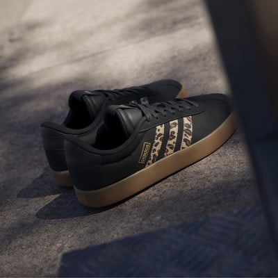 Fekete Adidas cipők leopárdmintás csíkokkal és gumitalppal.