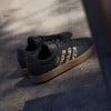 Fekete Adidas cipők leopárdmintás csíkokkal és gumitalppal.