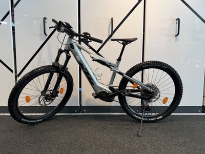 Graues E-Mountainbike mit Federung und breiten Reifen.
