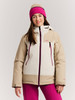 Mädchen in einer beige Winterjacke mit violetten Details und rosa Mütze.