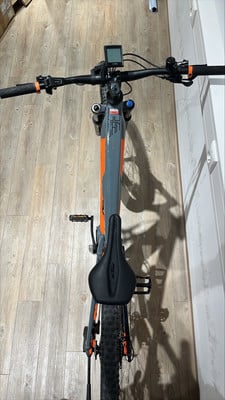 Ein KTM E-Mountainbike mit orangefarbenen Details auf Holzboden. Ein KTM E-Mountainbike mit orangefarbenen Details auf Holzboden.