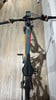 Ein KTM E-Mountainbike mit orangefarbenen Details auf Holzboden.