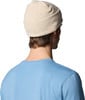 Mann mit beiger Mütze mit bunten Punkten und blauem T-Shirt.